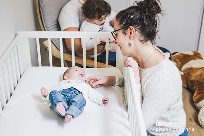 Parents penchés sur leur bébé dans son lit, séance naissance à domicile