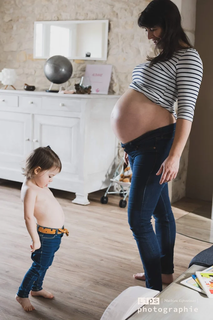 Future maman de profil et son aîné dans le salon, séance grossesse à domicile
