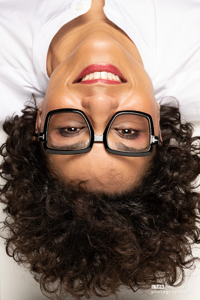 Portrait renversé d'une femme aux lunettes rondes sur fond blanc