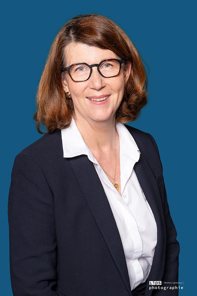 Portrait corporate d'une dirigeante en veste marine sur fond bleu