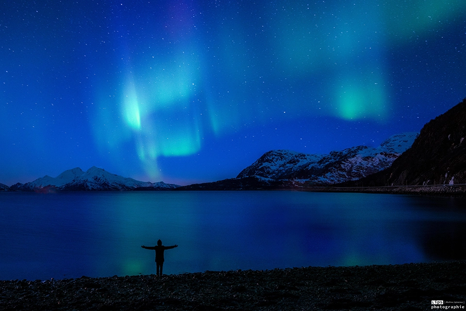 Aurore boréale au-dessus d'un fjord et silhouette d'un observateur, Laponie norvégienne