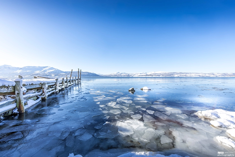 Plaques de glace flottant sur un lac arctique devant les montagnes, Norvège