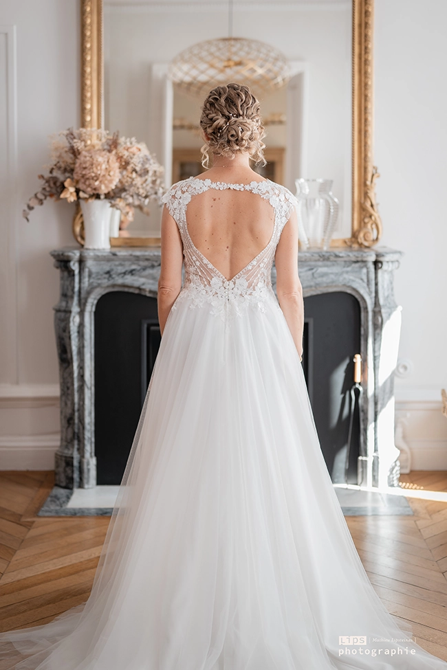 Mariée de dos devant une cheminée, dos en dentelle de la robe