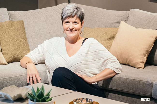 Portrait souriant d'une femme assise devant son canapé, séance à domicile dans la Vienne