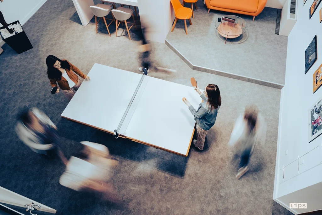 Vue plongeante sur un espace de travail collaboratif avec des personnes qui jouent au tennis de table et ses équipes en mouvement
