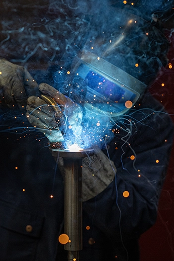 Soudeur à l'arc en gros plan, éclat bleu et projections d'étincelles