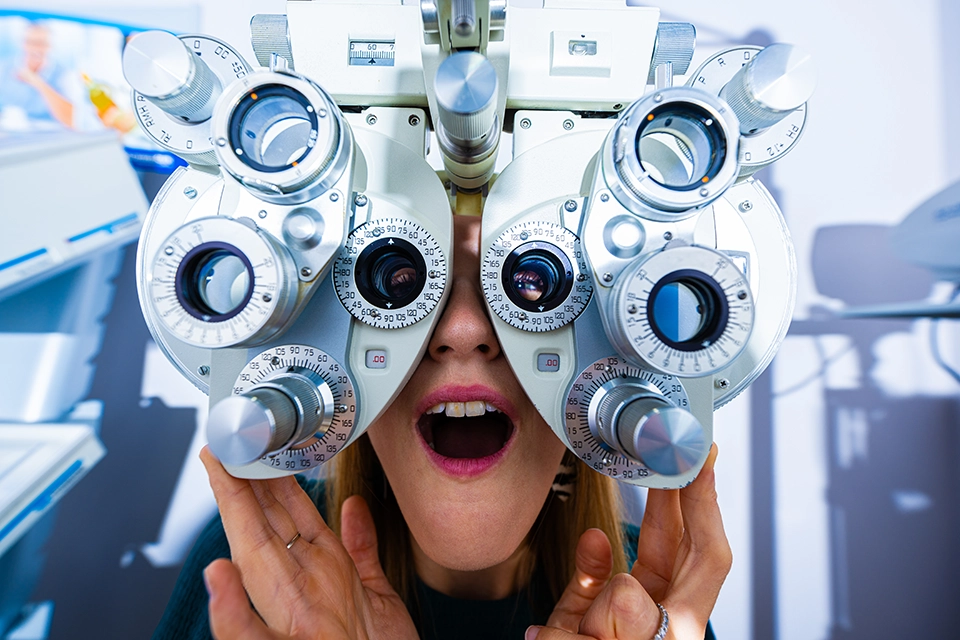 Cliente derrière un réfracteur lors d'un examen de vue chez un opticien