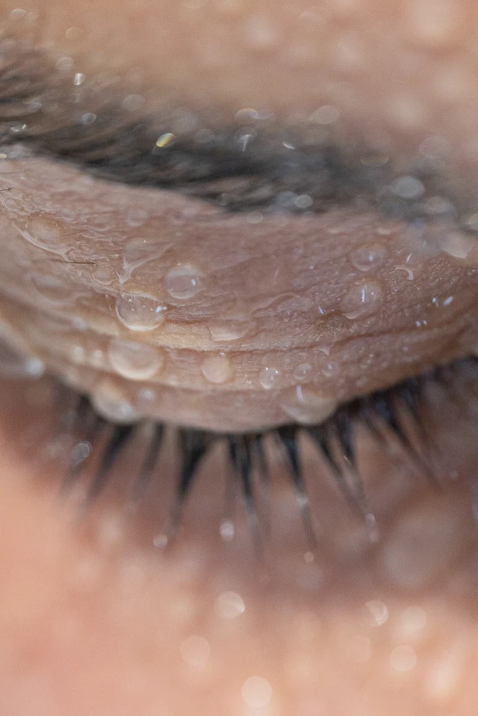 Macrophotographie d'un œil fermé et de gouttes d'eau sur les cils