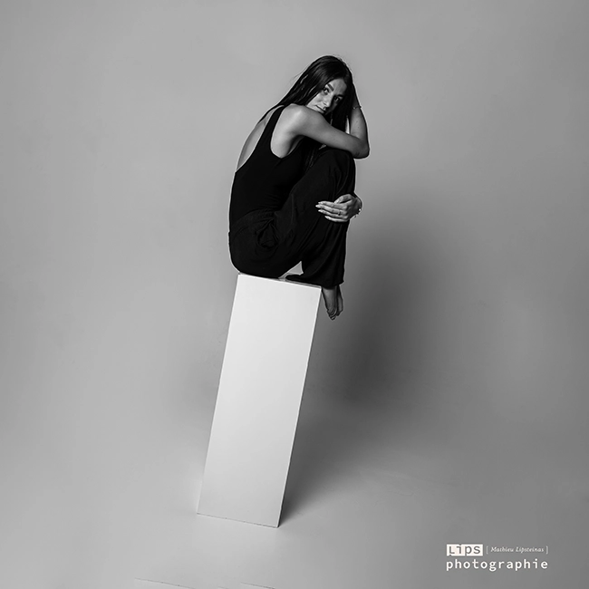 Silhouette d'une femme assise sur un cube blanc, portrait de studio en noir et blanc