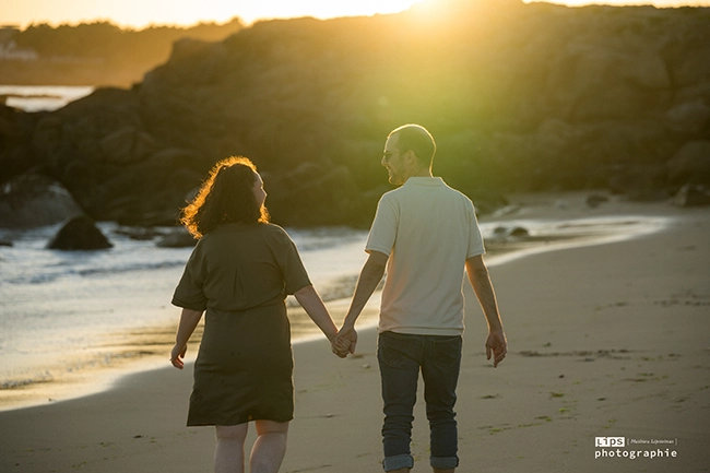Couple main dans la main sur la plage au coucher du soleil, séance en extérieur