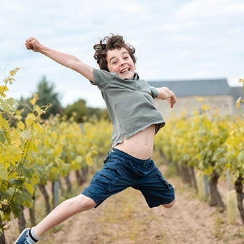 Enfant sautant bras écartés dans les vignes, photographie lifestyle en extérieur