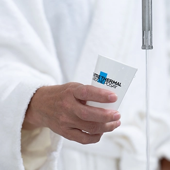 Main présentant un flacon devant une blouse blanche, photographie produit en laboratoire