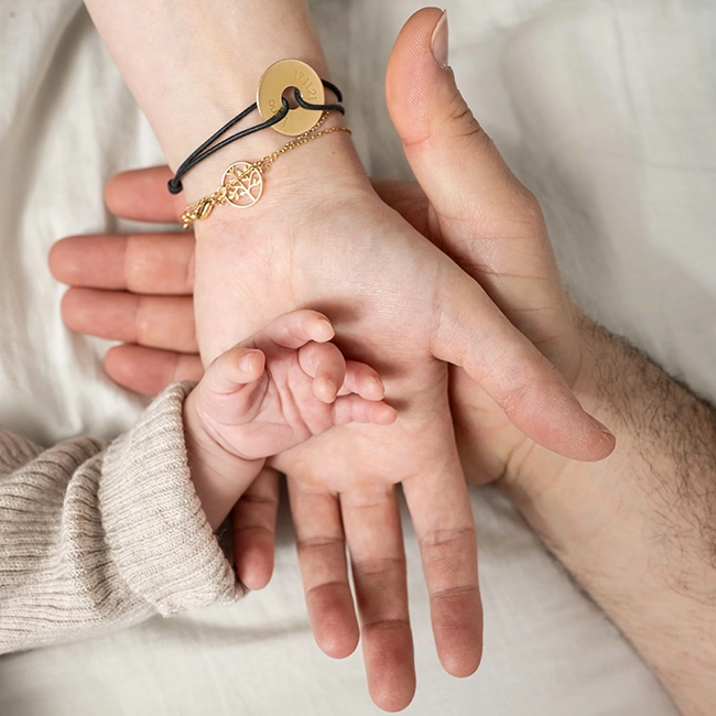 Gros plan sur les mains des parents et celles de leur nouveau-né, séance naissance